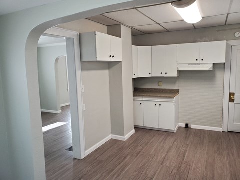 an empty kitchen with white cabinets and a wood floor