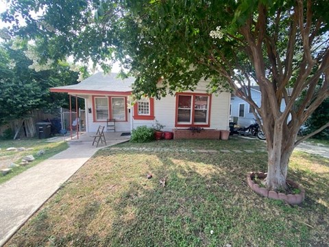 a small white house with a tree in front of it