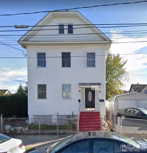A white house with a black door and red stairs.