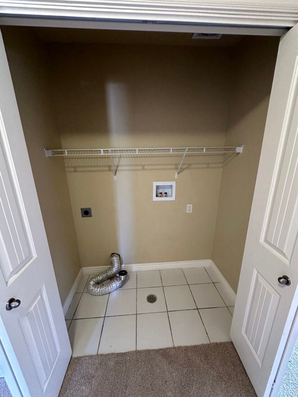 a bathroom with a closet and a drain on the floor