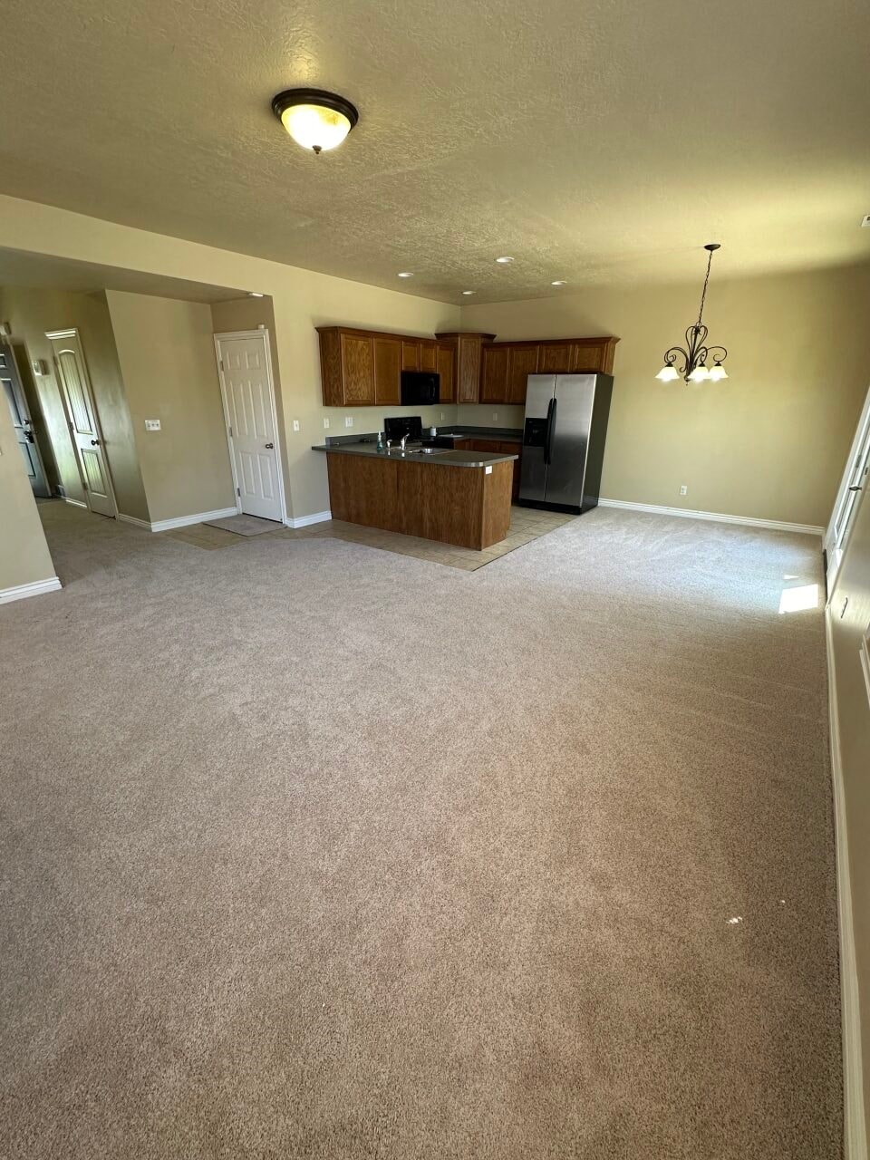 an empty living room and kitchen with a carpeted floor