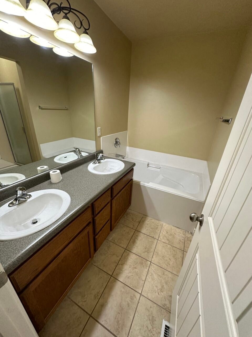 a bathroom with two sinks and a tub and a mirror