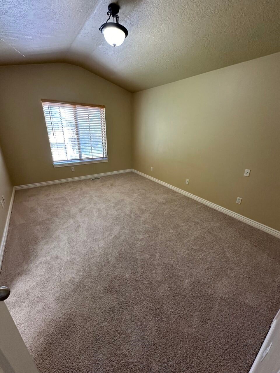 a large empty room with a window and carpet