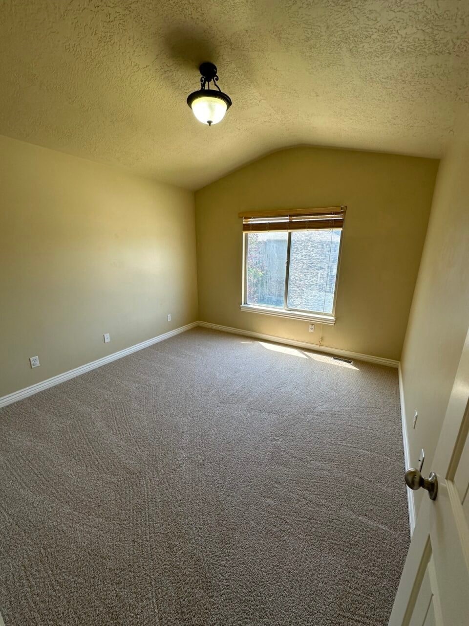 an empty living room with a window and carpet