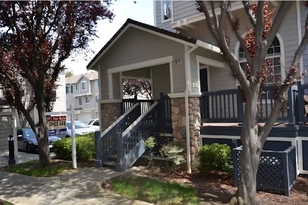 a house with a porch and stairs in front of a parking lot