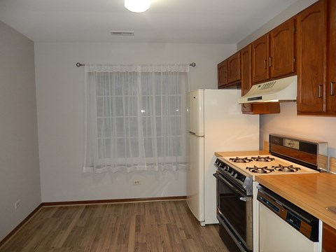 a kitchen with white appliances and wood flooring and a refrigerator