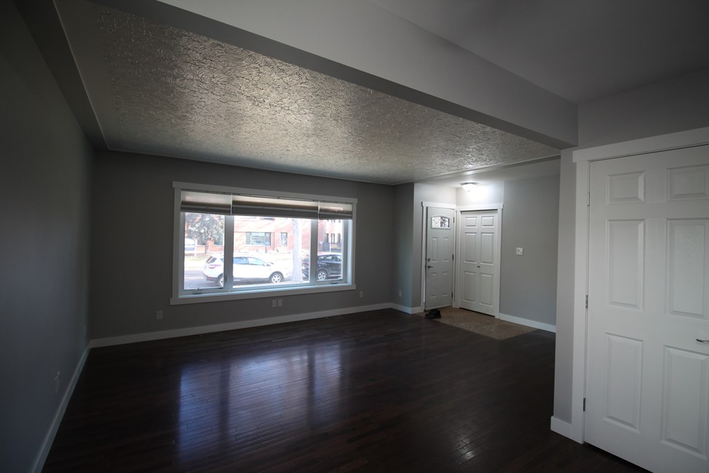 an empty living room with wood floors and a large window