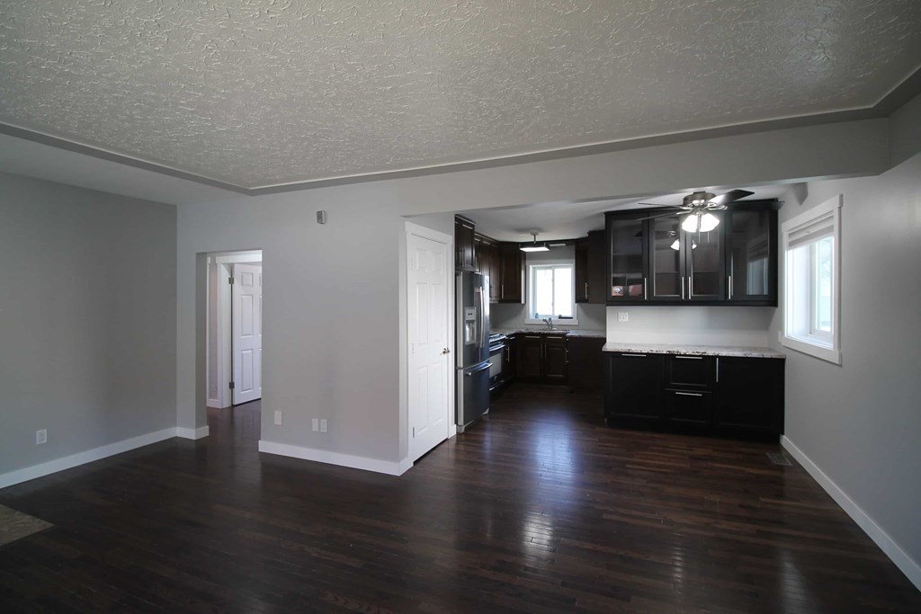 an empty living room and kitchen with hard wood floors