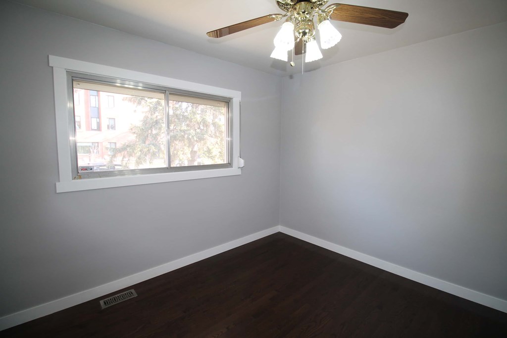 a bedroom with a window and a ceiling fan