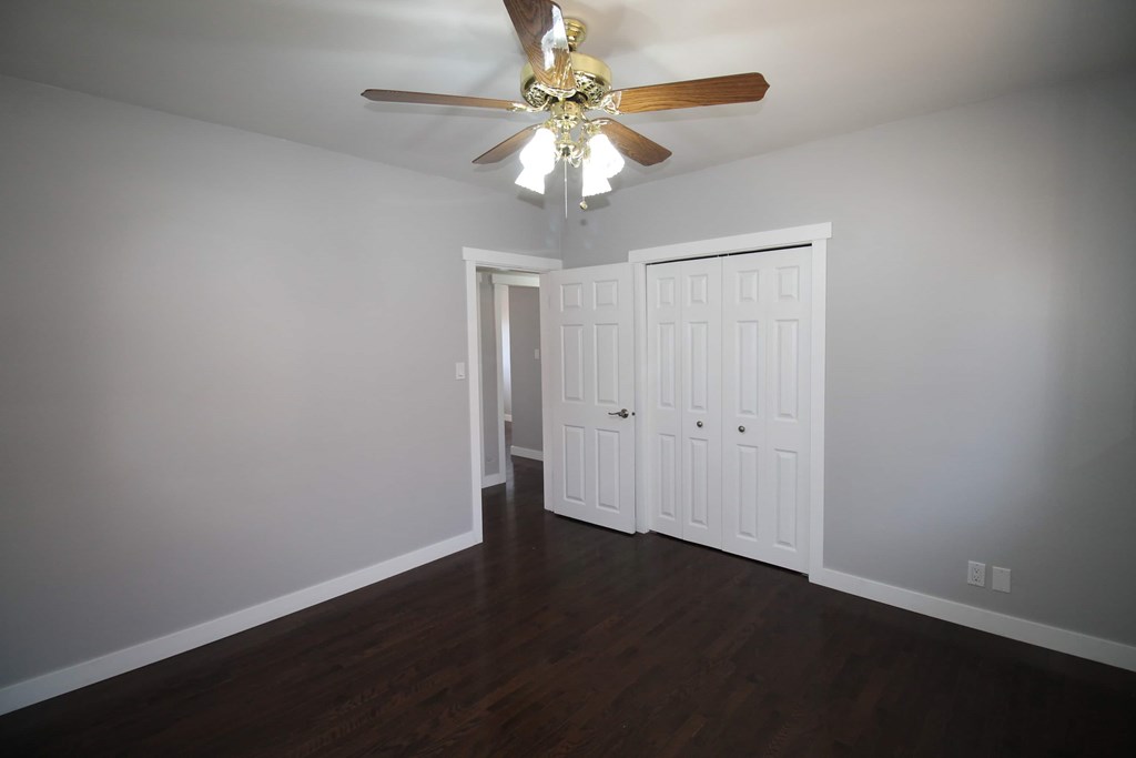 a living room with a ceiling fan and a door to a closet