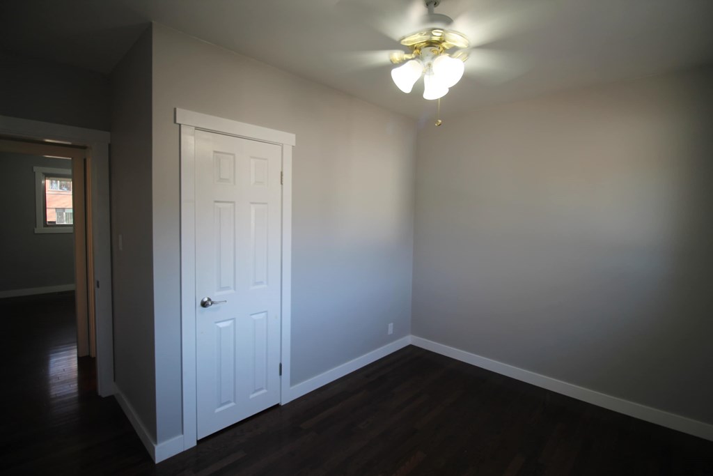 a bedroom with a white door and a ceiling fan