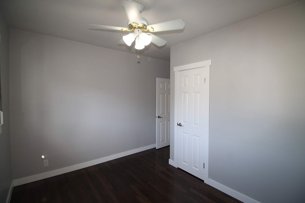 a bedroom with a ceiling fan and a white door