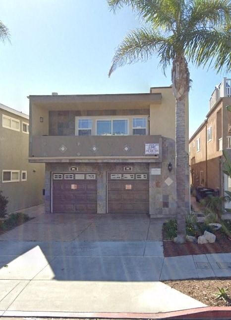 a house with a palm tree in front of a driveway