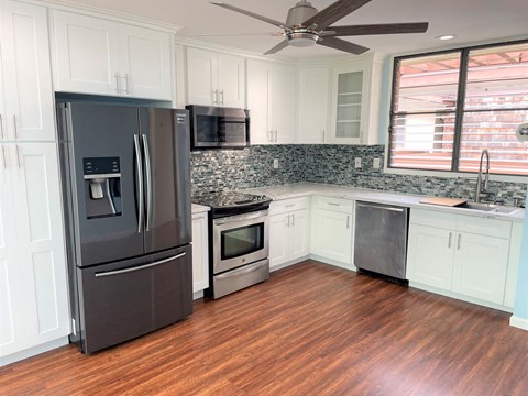 A kitchen with a black fridge and wooden floors.