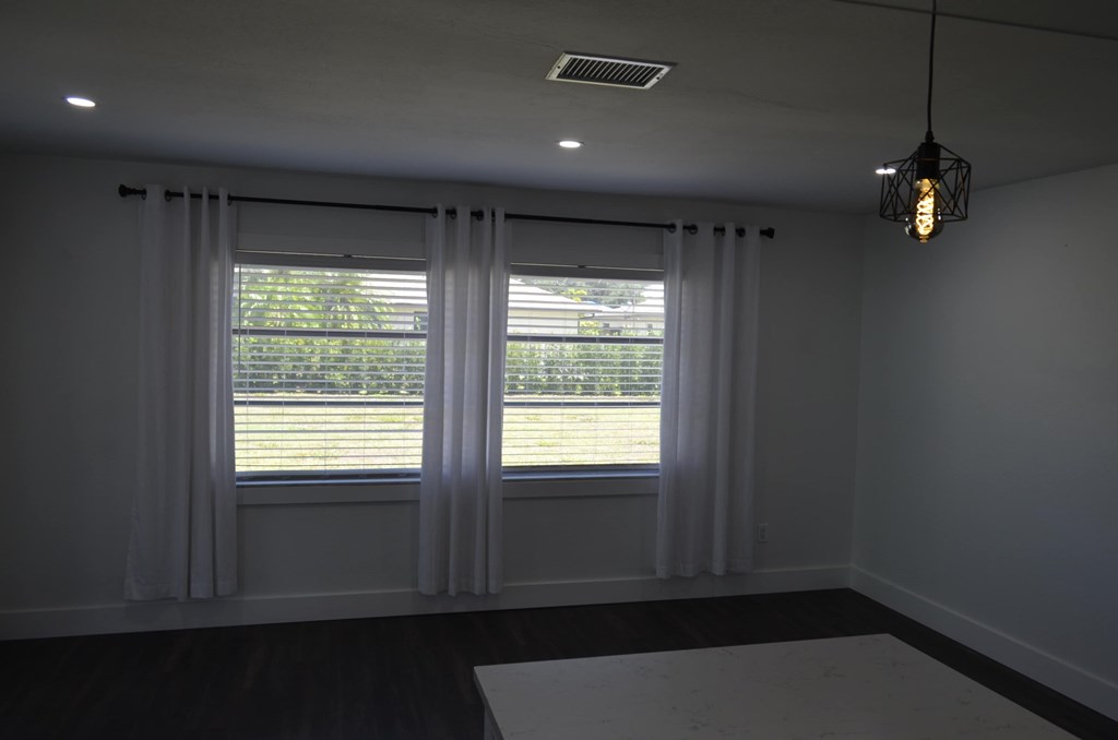 a living room with two windows and white curtains