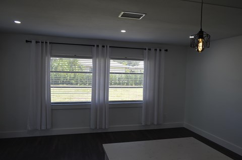 a living room with two windows and white curtains