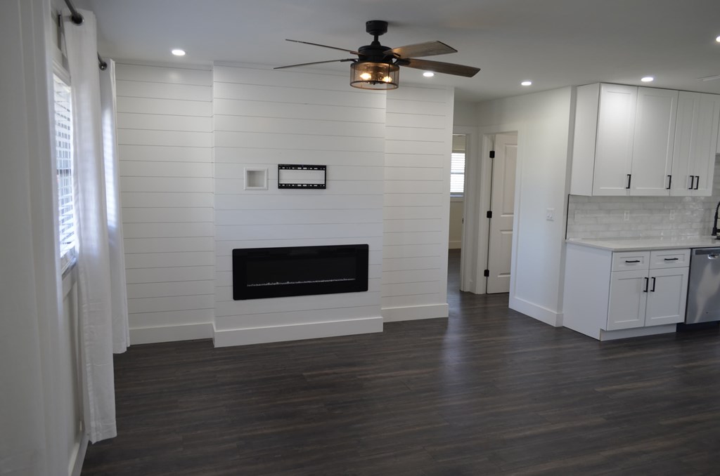 a white living room with a fireplace and a ceiling fan