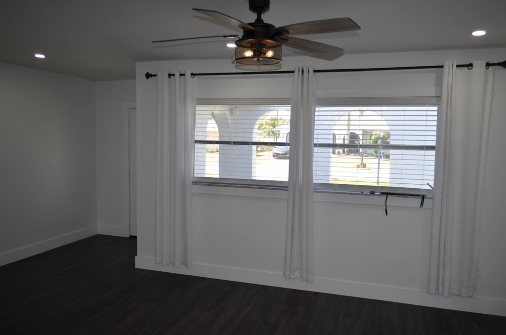 an empty living room with a ceiling fan and a window