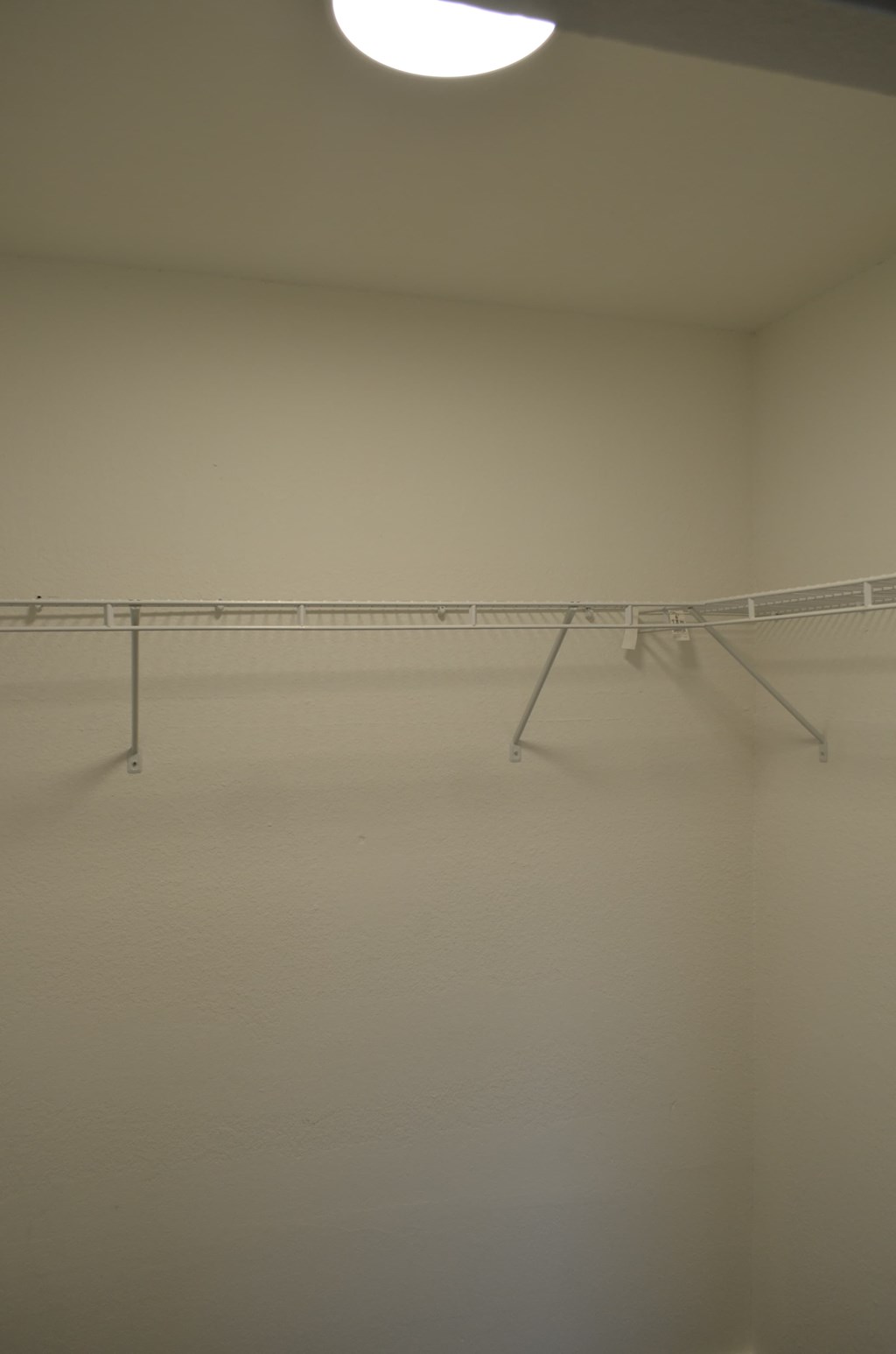 a white room with a light on the ceiling and several clothes racks