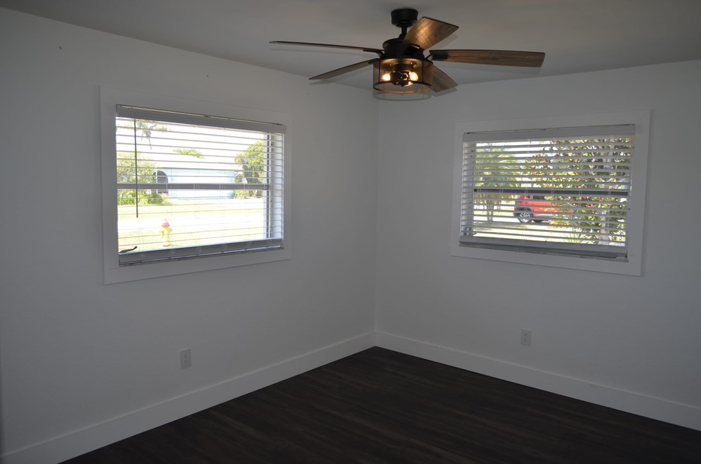 a living room with a ceiling fan and two windows