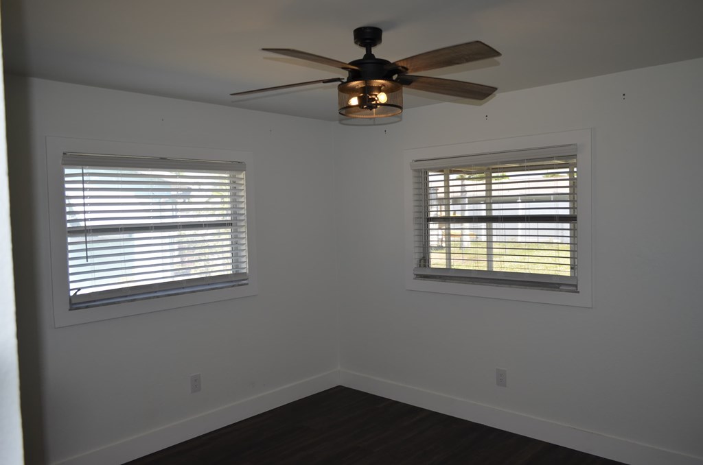 a living room with a ceiling fan and two windows