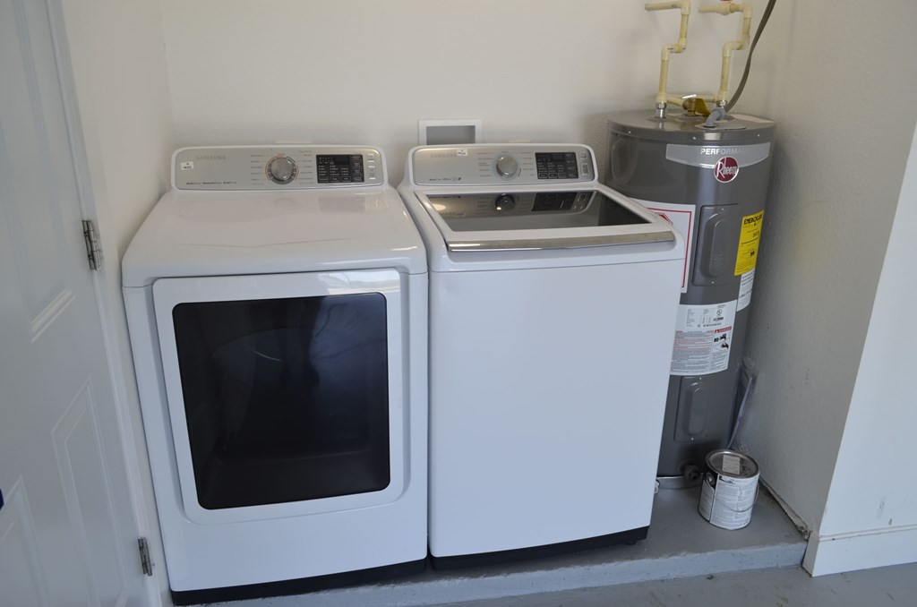 two washing machines in a kitchen next to a water heater