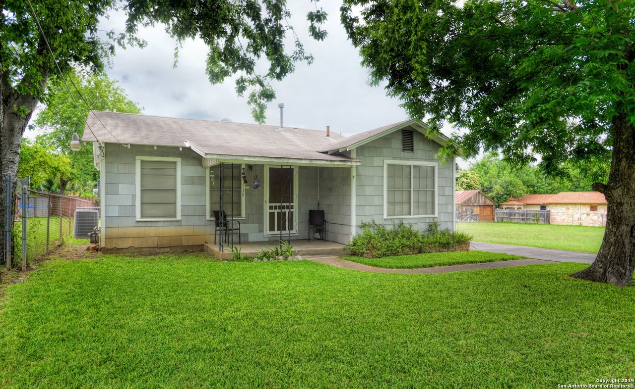 a small green house with a yard and a tree