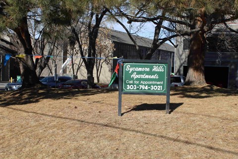 A sign for Sycamore Hills Apartments is displayed in a grassy area.