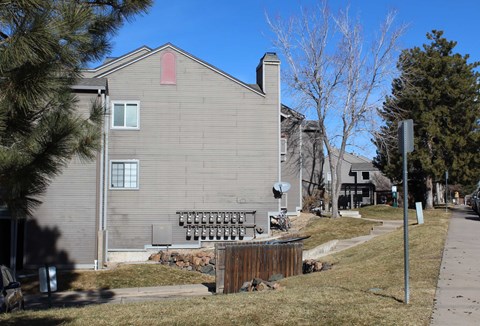 A grey house with a red roof and a satellite dish on the roof.