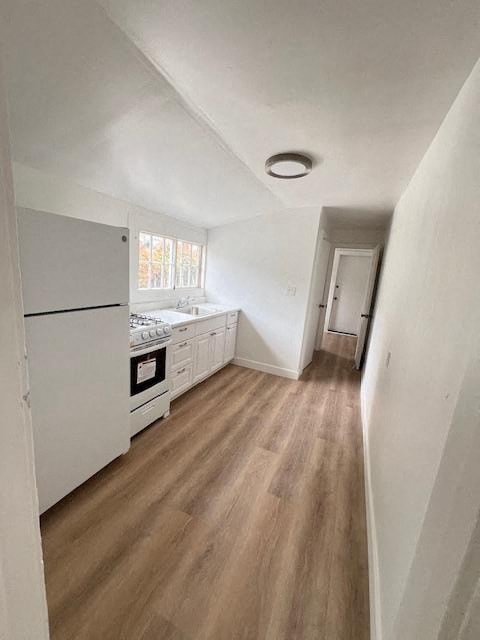 a kitchen with white appliances and a wooden floor