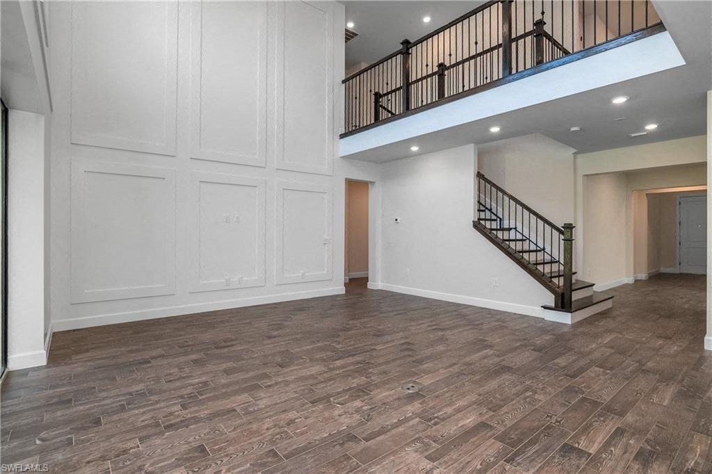 the living room and staircase of a new home with white walls and wood floors