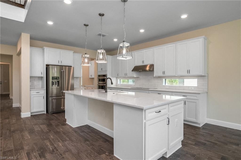 a large white kitchen with white cabinets and stainless steel appliances