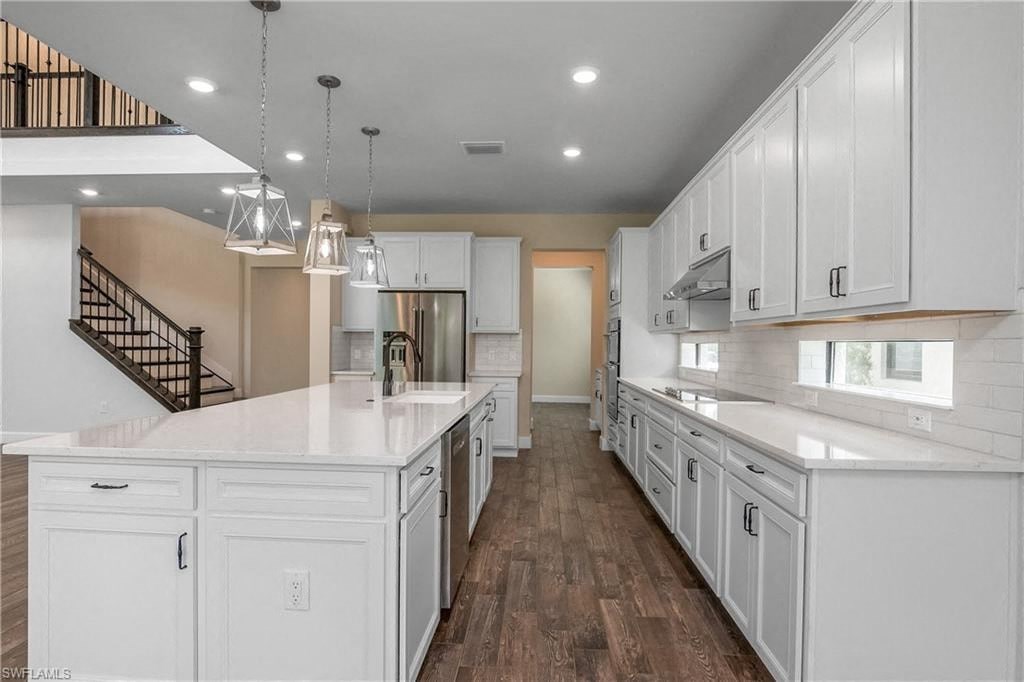 a large white kitchen with white cabinets and a staircase