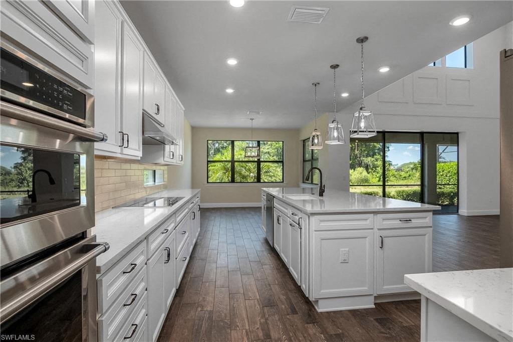 a large kitchen with white cabinets and a wood floor