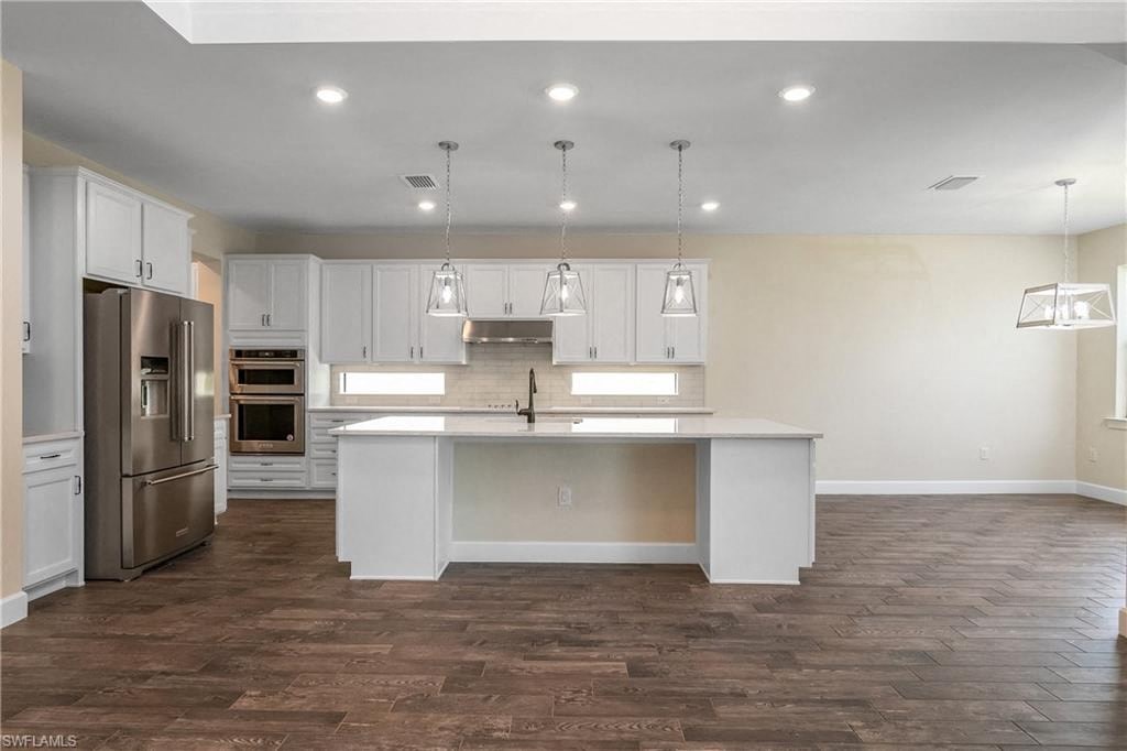 a large kitchen with white cabinets and a stainless steel refrigerator