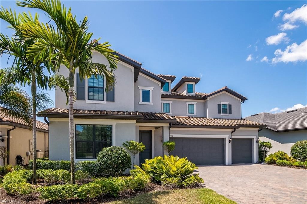 a house with a garage and palm trees in front of it