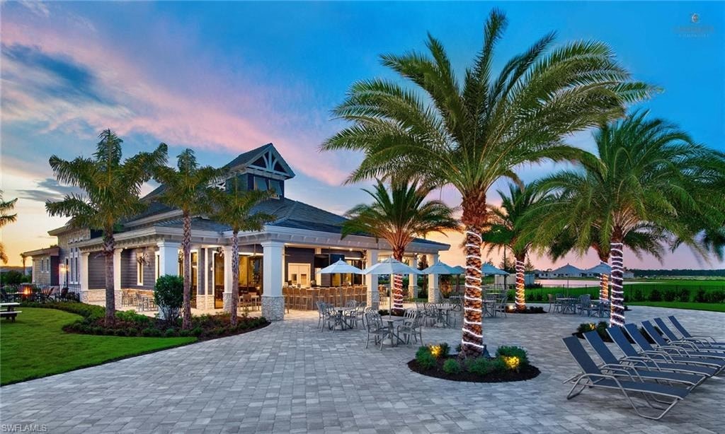 a patio with chairs and palm trees in front of a house