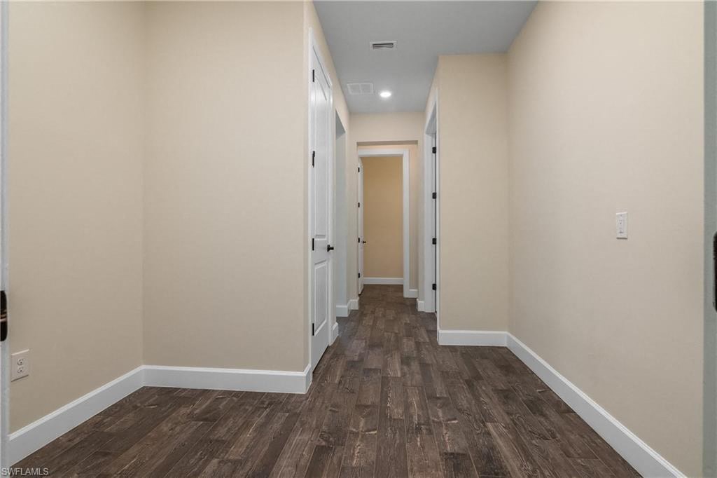 a long hallway with wood flooring and white walls