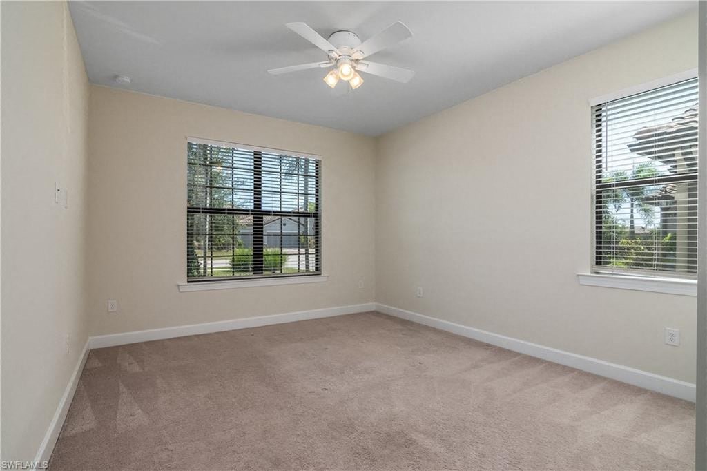 an empty bedroom with a ceiling fan and a window