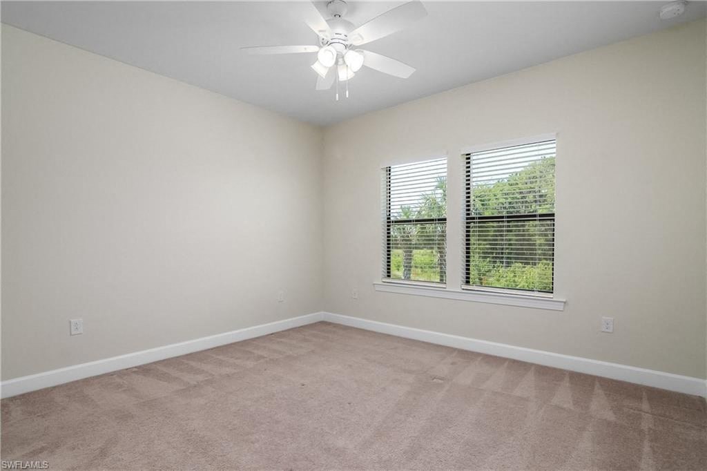 an empty living room with a window and a ceiling fan