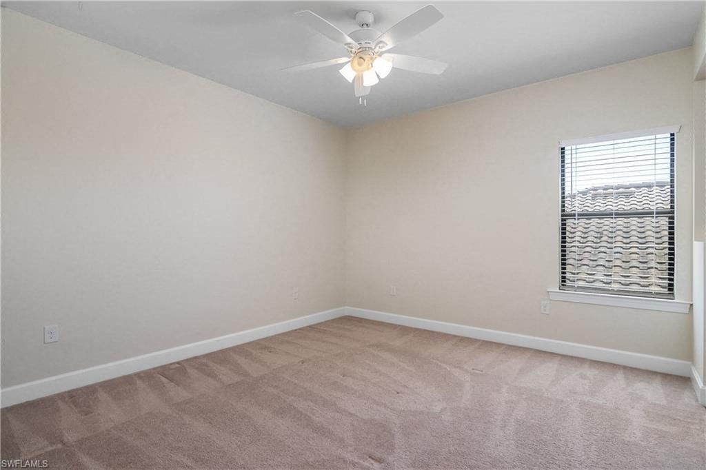 an empty living room with a ceiling fan and a window
