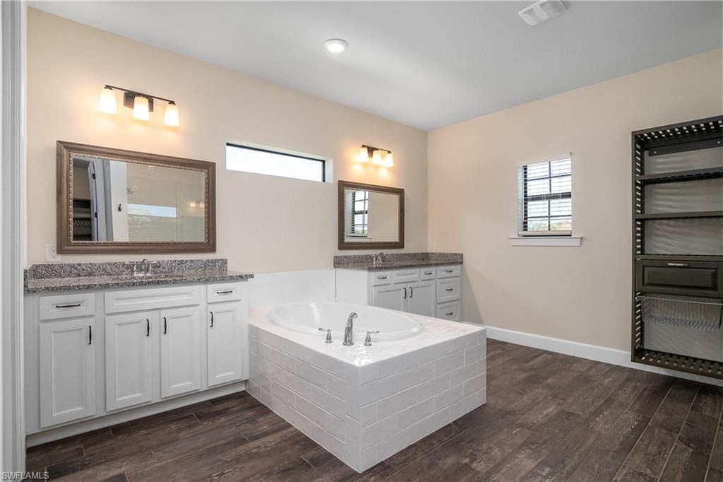 a large white bathroom with a tub and two sinks