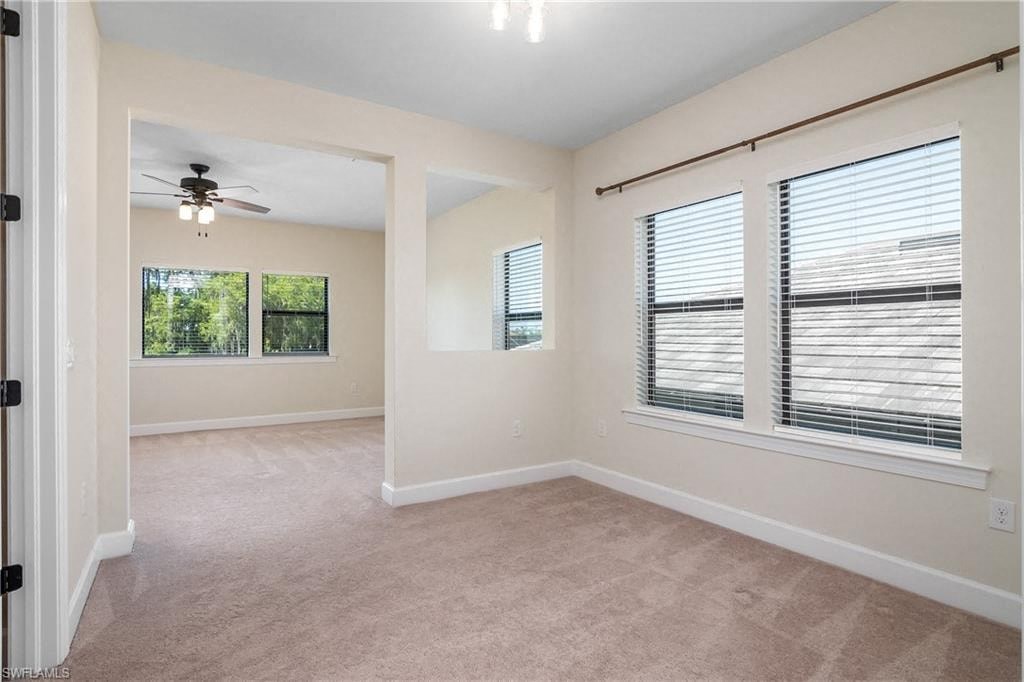 an empty living room with windows and a ceiling fan