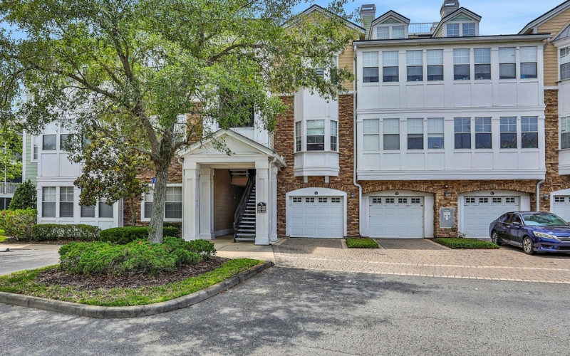 the front of an apartment building with a car parked in front