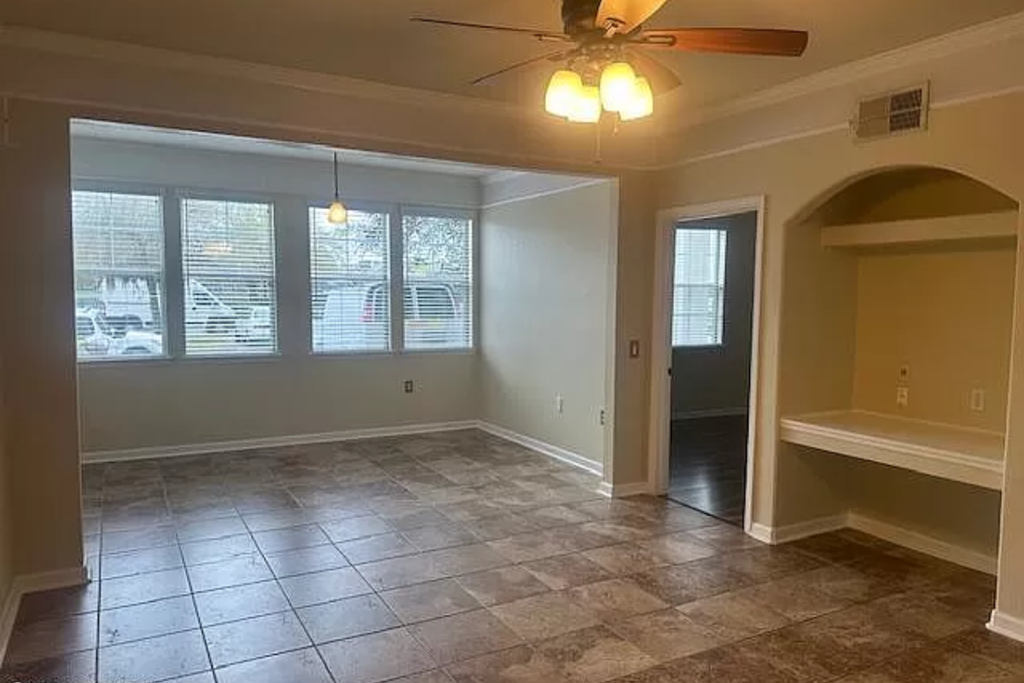 an empty living room with a ceiling fan