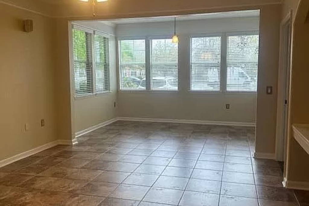 an empty living room with windows and a tiled floor