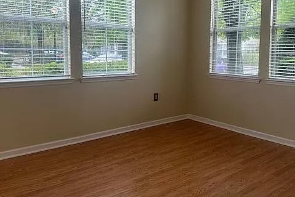 an empty room with two windows and a wooden floor