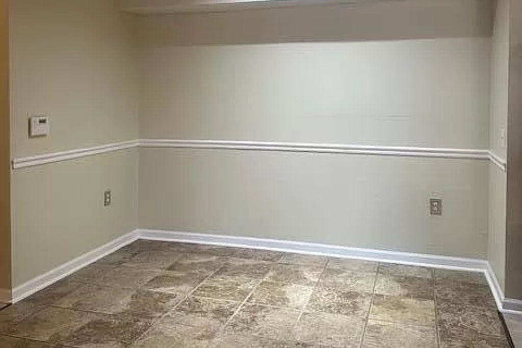 a empty room with a white wall and a tiled floor