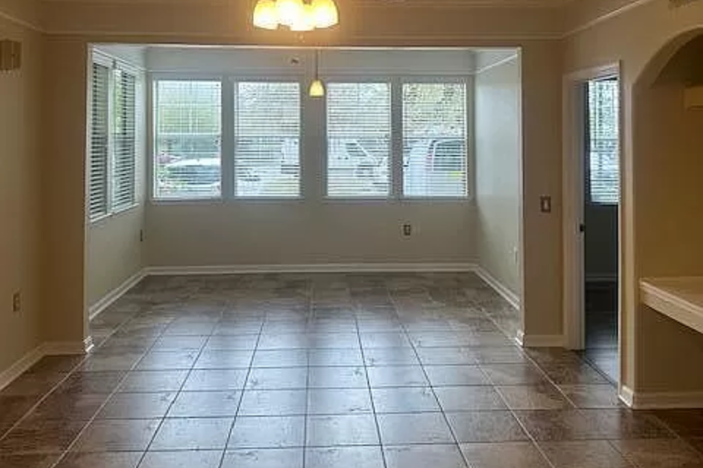 an empty living room with windows and a tiled floor