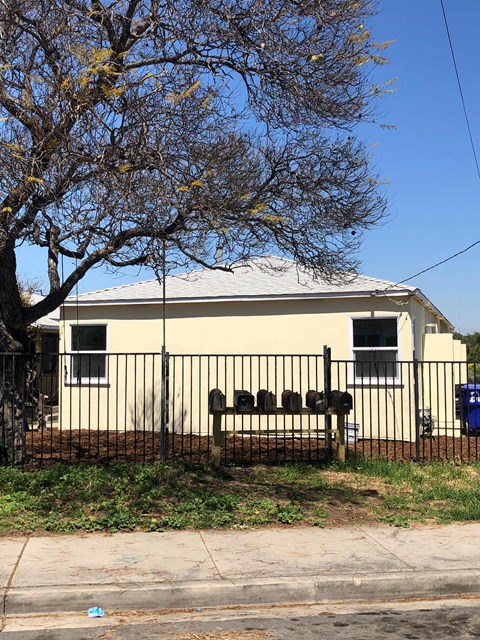 A house with a black fence and a tree in front of it.